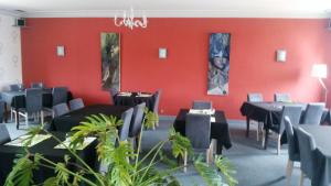 une salle à manger avec des tables et des chaises et un mur rouge dans l'établissement Le Richelieu, à Saint-Jean-de-Monts