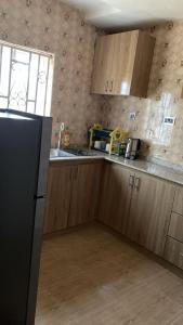 een keuken met houten kasten en een zwarte koelkast bij SHORT Rental in Ilorin