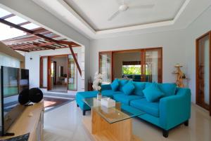 Una sala de estar con un sofá azul y una mesa. en Sudha Villa Bali A, en Seminyak
