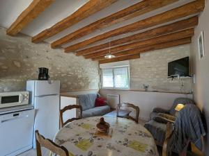 a kitchen and living room with a table and a refrigerator at Ancienne ferme avec jardin, trampoline et pétanque entre Valençay et Beauval - FR-1-591-217 in Frédillé