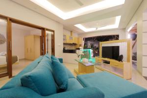 Una sala de estar con un sofá azul y un televisor. en Sudha Villa Bali A, en Seminyak