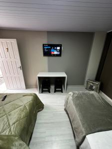 a bedroom with a bed and a desk with a tv on the wall at Loft Lux 7 in Chapecó