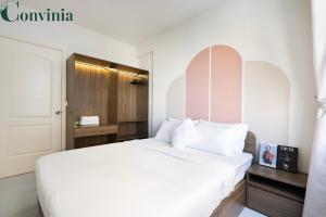 ホーチミン・シティにあるSoho Apartment By Conviniaの白いベッドと木製キャビネット付きのベッドルーム1室が備わります。