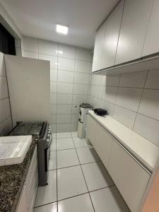 a kitchen with white tiled walls and white appliances at Apartamento ao lado patio forro in Caruaru