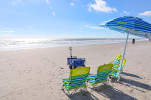 two chairs and an umbrella on the beach at Shello Chalet, a quiet home close to the beach in Myrtle Beach
