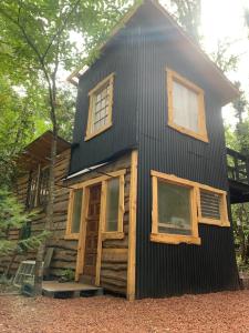a cabin with a black roof and windows at Cabaña bosque in Recinto