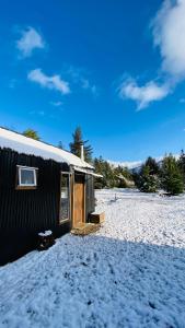 un bâtiment avec de la neige sur le sol à côté dans l'établissement Melitrekan Cabaña para dos personas, à Melipeuco