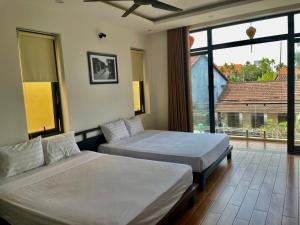 2 Betten in einem Zimmer mit einem großen Fenster in der Unterkunft Thuong Da Riverside Homestay in Hoi An