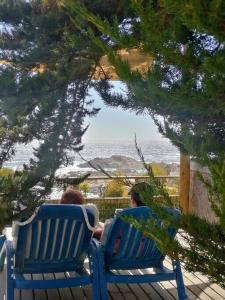 埃爾基斯科的住宿－CasaMar ElQuisco，两个人坐在蓝色长椅上,看着大海