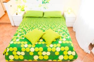 a bed with green and yellow polka dot sheets and pillows at B&B Arcobaleno Affittacamere Rainbow in Alessandria