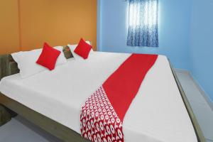 a bed with red and white pillows on it at Flagship Youngsky in Gulzārbāgh