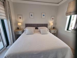 a bedroom with a large white bed with two windows at Beautiful 2-Bed Villa in Quinta do Lago with Pool in Quinta do Lago