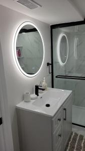 a white bathroom with a sink and a mirror at One Bedroom Apartment in Ajax