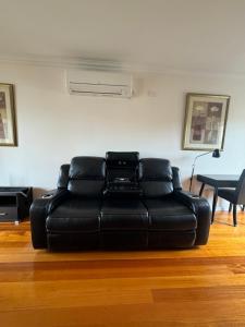 un sofá de cuero negro sentado en una sala de estar en Banyan Place, en Warrnambool
