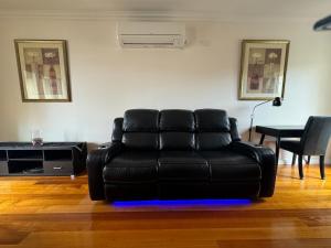 a black leather couch in a living room with a table at Banyan Place in Warrnambool