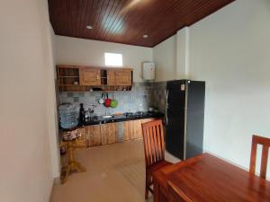 a kitchen with a black refrigerator and wooden cabinets at Molog guest house in Ubud