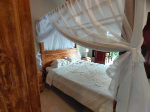 a bedroom with a canopy bed with white sheets and pillows at Molog guest house in Ubud