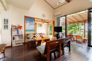 Beach House Yomitan في يوميتان: غرفة معيشة مع طاولة وكراسي وإطلالة على المحيط
