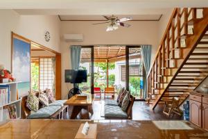 sala de estar con escalera, sofá y mesa en Beach House Yomitan, en Yomitan