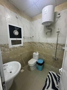 a bathroom with a white toilet and a sink at Maison Masirah in Şūr Maşīrah