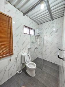 W łazience znajduje się toaleta i przeszklony prysznic. w obiekcie villa lestari w mieście Cipanas