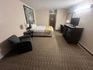 une chambre d'hôtel avec un lit, un canapé et une télévision dans l'établissement Super 8 by Wyndham Sturgis, à Sturgis