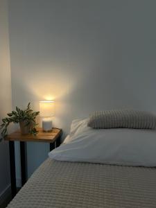 a bed with a table with a lamp on it at Włostowicka Ostoja Apartament in Puławy