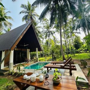 a resort with a pool and a table and chairs at Elegant Hamlets Home Stay in Chilaw