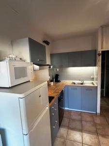una cocina con electrodomésticos blancos y armarios azules en soulac sur mer, maison dans résidence proche plage, en Soulac-sur-Mer