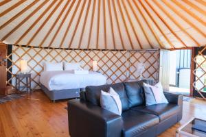 a room with a couch and a bed in a yurt at Awaawa Yurts - Tane Yurt in Palm Beach