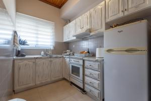 a kitchen with white cabinets and a white refrigerator at Elviras houses II in Agria