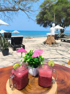 two mason jars with drinks on a table next to a beach at Buda House Beach in Playa Blanca