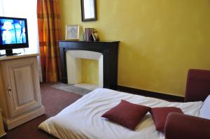 1 dormitorio con 1 cama con chimenea y TV en Hôtel Du Herrenstein, en Neuwiller-lès-Saverne