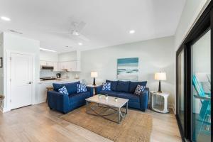 una sala de estar con 2 sofás azules y una mesa. en Palms of Seagrove C13 - Gulf Front, Bikes, Pool Sleeps 6, en Seagrove Beach