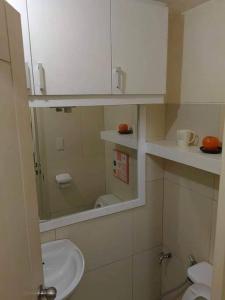 La salle de bains est pourvue d'un lavabo, d'un miroir et de toilettes. dans l'établissement Chateau Elysee A22 near bar resto mall Airport, à Manille