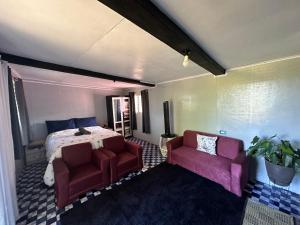 a bedroom with a bed and two red chairs at John and Agnes Nicol 