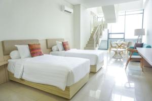 two beds in a white room with a staircase at Skysuites Residence in Kedungbaruk