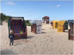 a little boy standing on the beach next to a beach chair at Verpust Comfortable holiday residence in Horumersiel