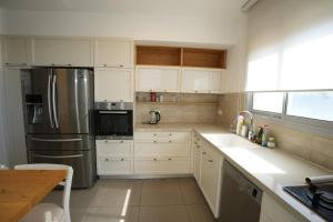 uma cozinha com armários brancos e um frigorífico de aço inoxidável em Specious Pastoral And Attractive 5 Bedroom Apartment Center Hod Hasharon em Hod HaSharon