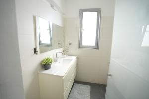 a white bathroom with a sink and a mirror at Specious Pastoral And Attractive 5 Bedroom Apartment Center Hod Hasharon in Hod HaSharon