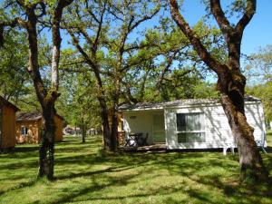 派拉克CAMPING LES PAILLOTES的一座小白色小屋,位于一个树木繁茂的院子内