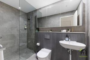 uma casa de banho com um WC, um lavatório e um chuveiro em Vivid condo with Pool in Olympic Park em Sydney