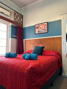 Un dormitorio con una gran cama roja con almohadas azules en North Gregory Hotel en Winton