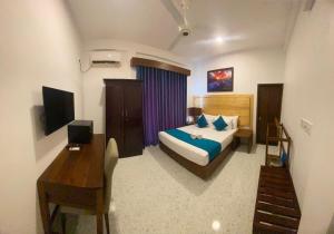 um quarto com uma cama, uma secretária e uma televisão em Trinco Beach Resort em Trincomalee