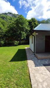 um pequeno edifício com um campo de relva e árvores em Villa Kaan em Trnovo