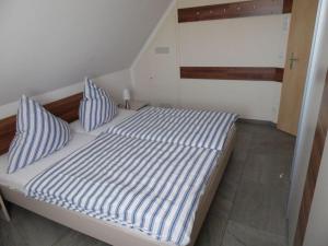 a bed with blue and white striped sheets and pillows at Just before the cape, holiday home B in Putgarten