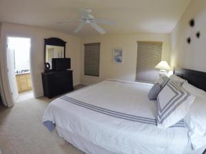 Schlafzimmer mit einem weißen Bett und einem Deckenventilator in der Unterkunft Panoramic 4BR Superior Pool Home near Disney in Davenport