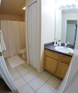ein Badezimmer mit einem Waschbecken, einem WC und einem Spiegel in der Unterkunft Panoramic 4BR Superior Pool Home near Disney in Davenport