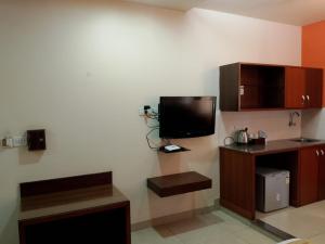 Habitación con TV en la pared y escritorio. en Cubbon Suites - 10 Minute walk to MG Road, MG Road Metro and Church Street, en Bangalore