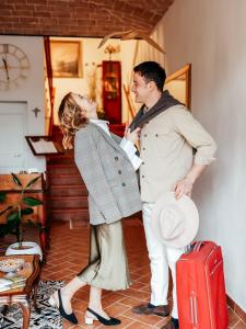 une femme debout à côté d'un homme avec une valise rouge dans l'établissement Casa Due Marie Marano sul Panaro, à Marano sul Panaro